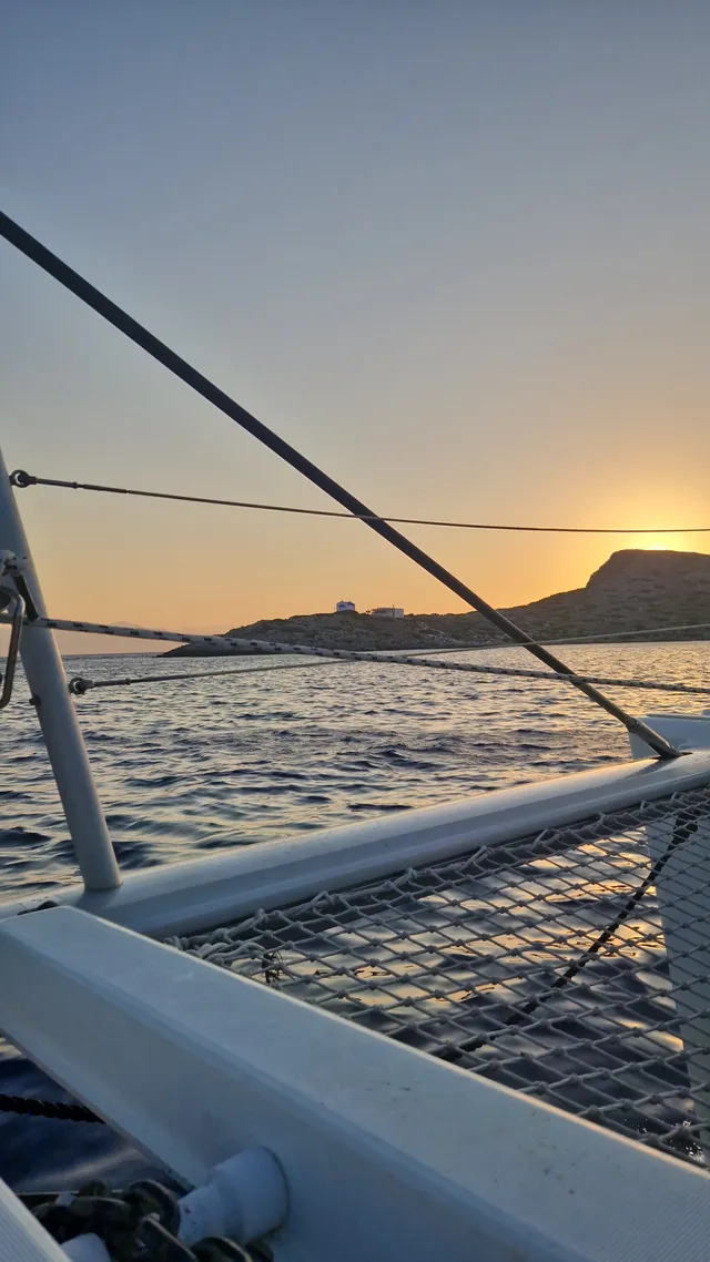 Sunset over the water, with the ropes and deck of a boat in the foreground.